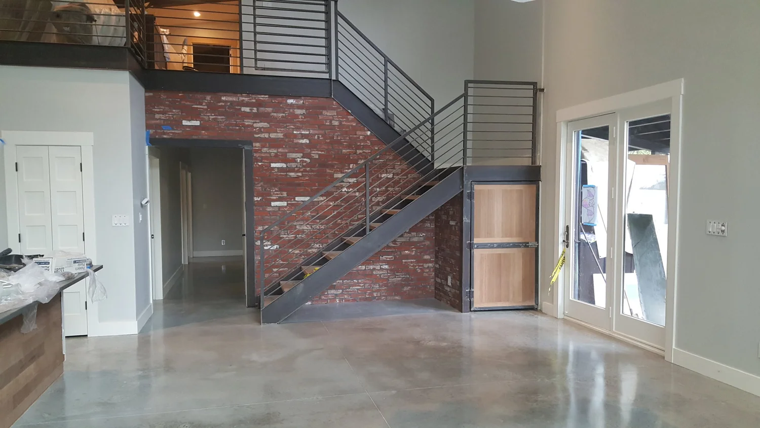 Gray polished concrete floor next to a brick wall and a metal staircase